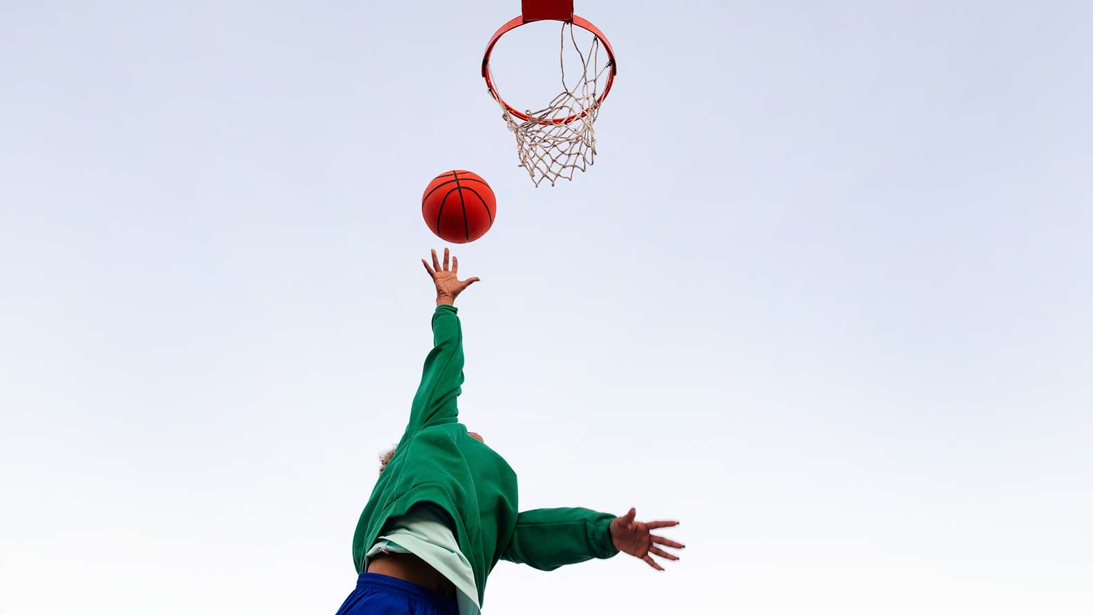 Person kastar basketboll mot korg